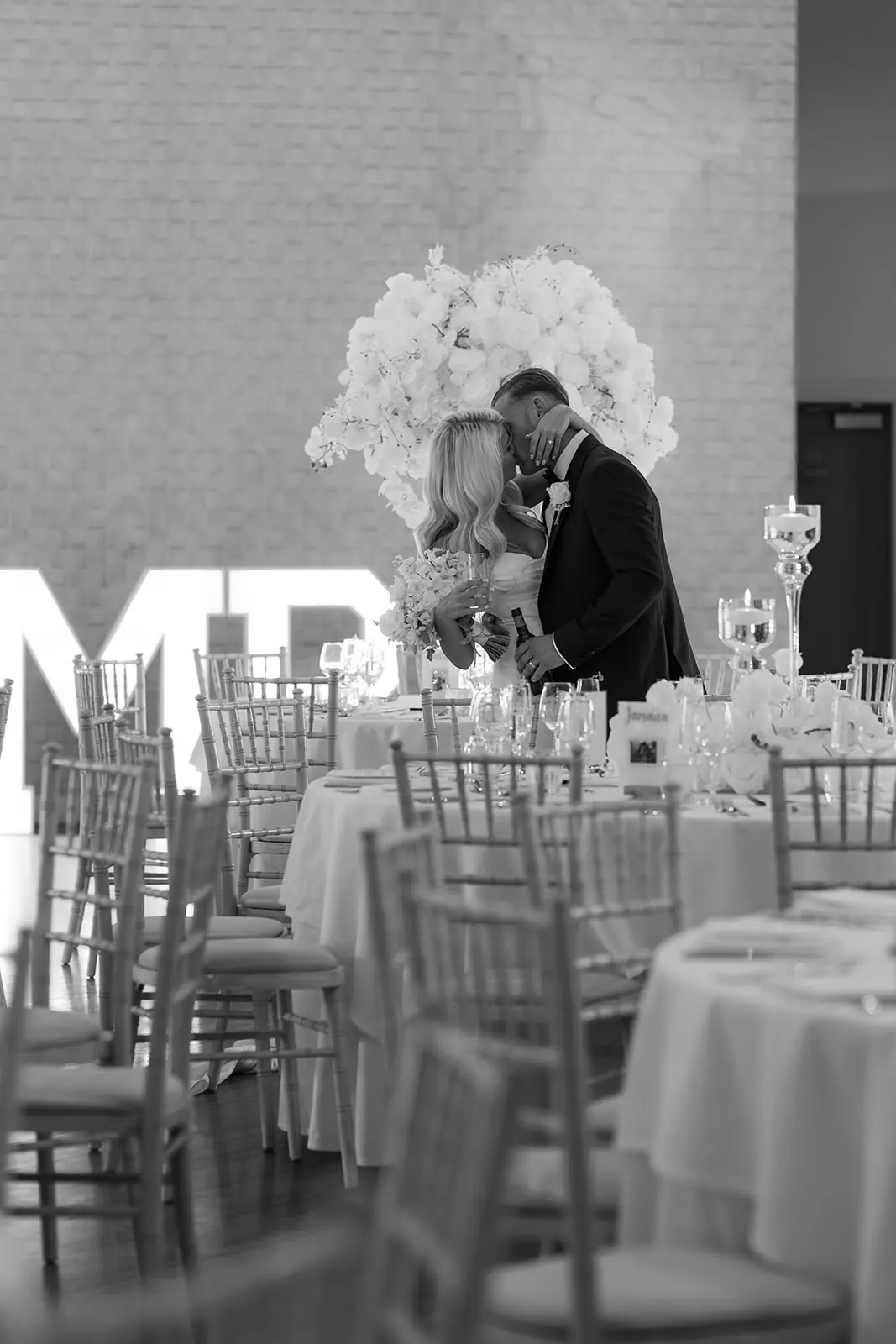 Bride and groom kissing in front of illuminated MR & MRS letters